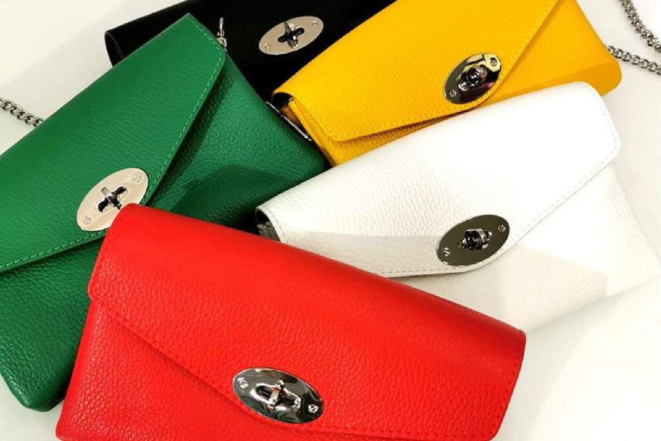 Punainen, vihreä, valkoinen, keltainen ja musta käsilaukku valkoisella alustalla